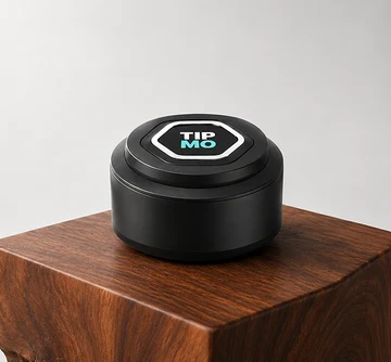TIPMO Counter Puck — a round black NFC puck with the TIPMO logo on a hexagonal face, resting on a polished wood block